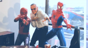 Stan Lee posing with Spider-Man statues